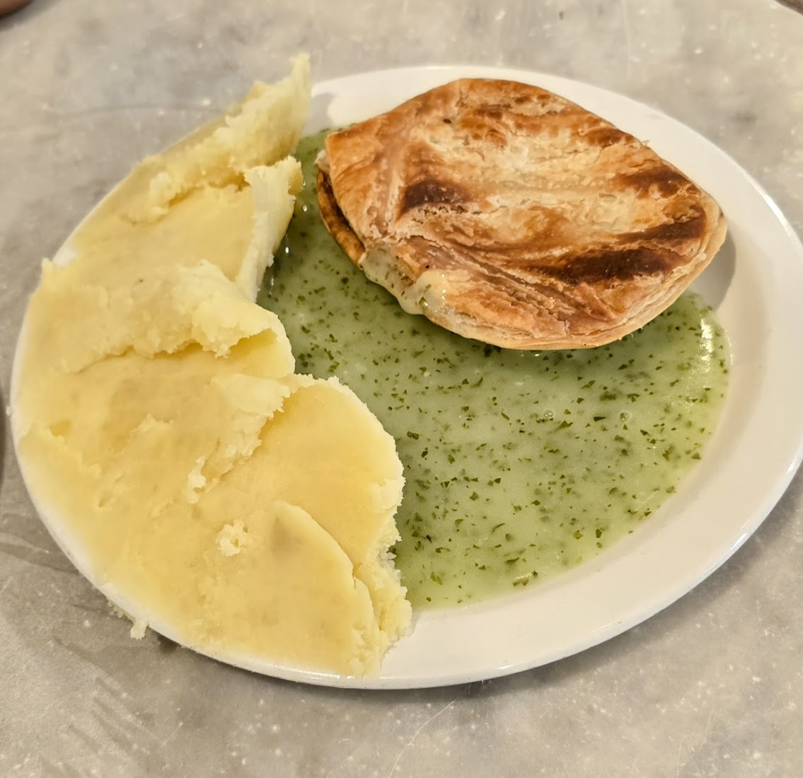 A traditional pie and mash with green liquor on marble at M. Manze